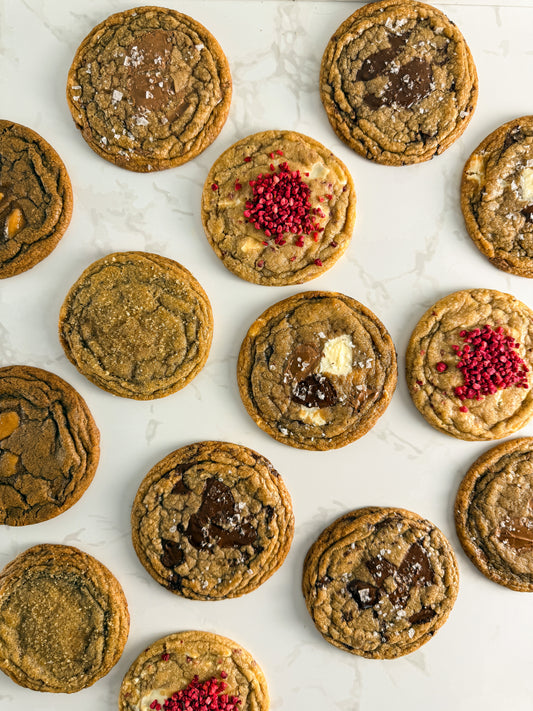 Six Half Three bakery-style cookies showing the full flavour range — triple choc, dark chocolate, milk chocolate, white chocolate and raspberry, espresso toffee, and Earl Grey and orange