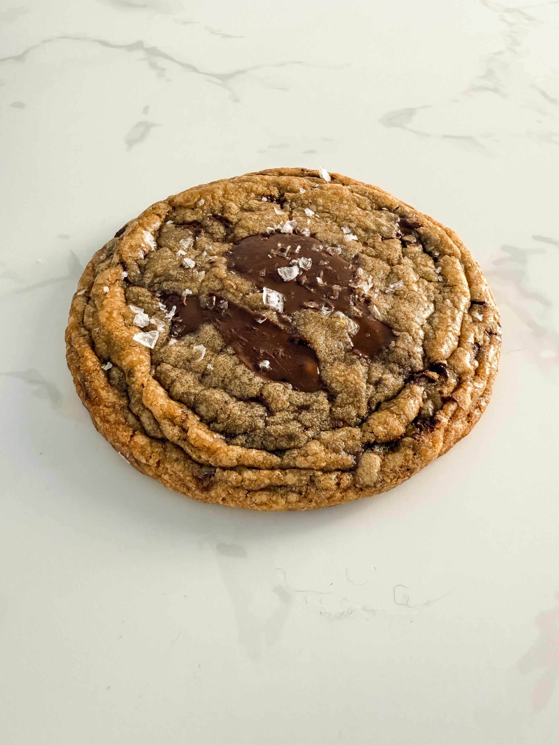 Half Three dark chocolate and sea salt cookie from above at an angle, showing crinkled edges and chewy centre