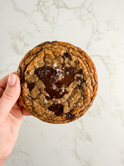 Hand holding a Half Three dark chocolate and sea salt cookie