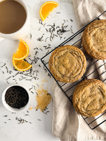 Half Three Earl Grey and orange cookie with loose leaf Earl Grey tea and fresh orange slices