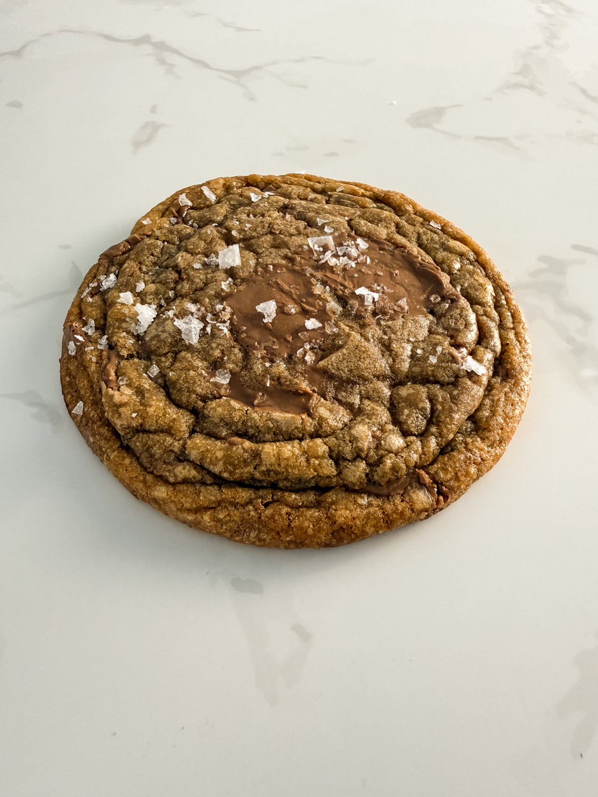 Half Three milk chocolate and sea salt cookie from above at an angle, showing thin chewy texture