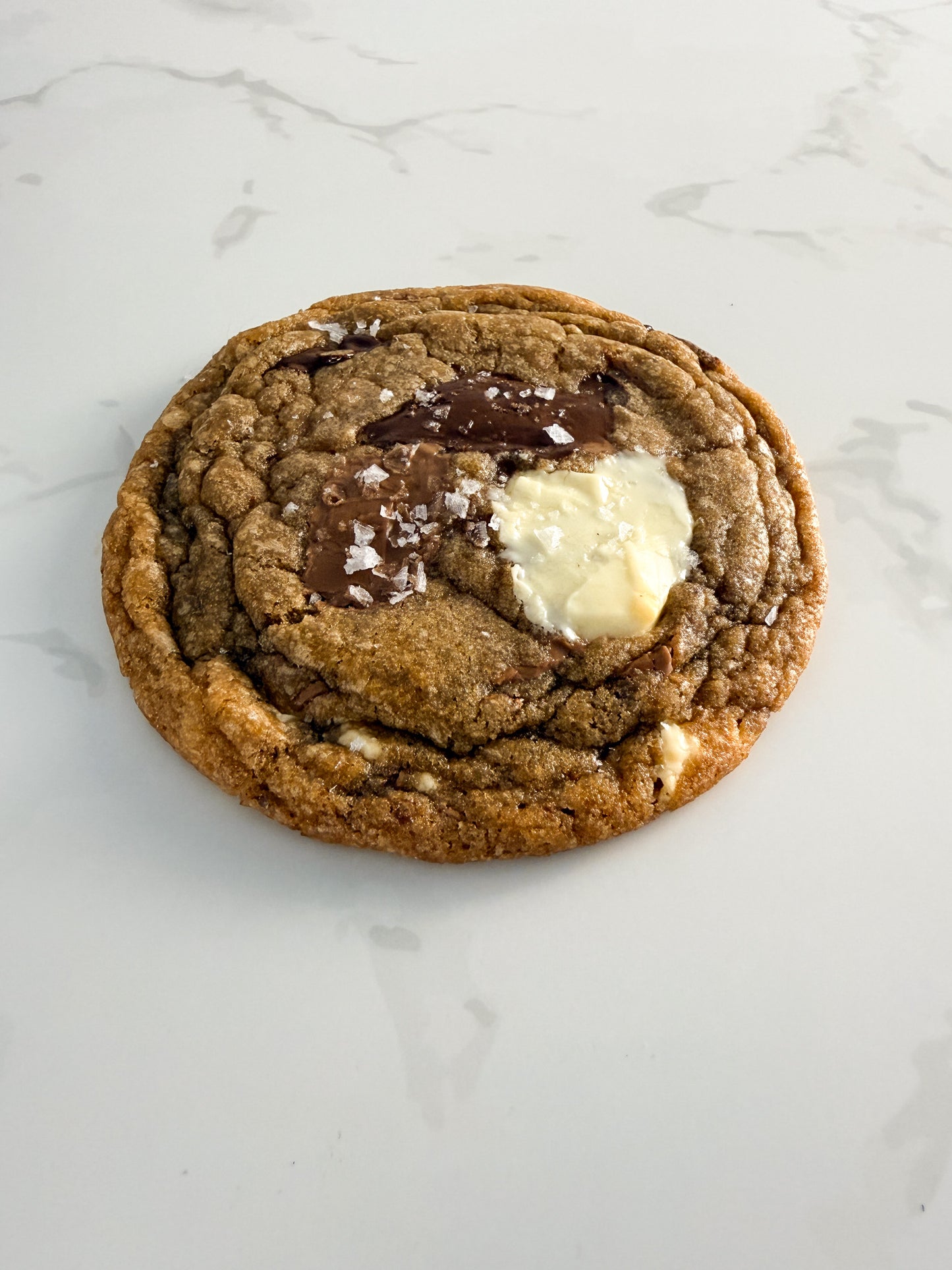 Half Three triple chocolate cookie from above at an angle, showing thin chewy texture and melted chocolate